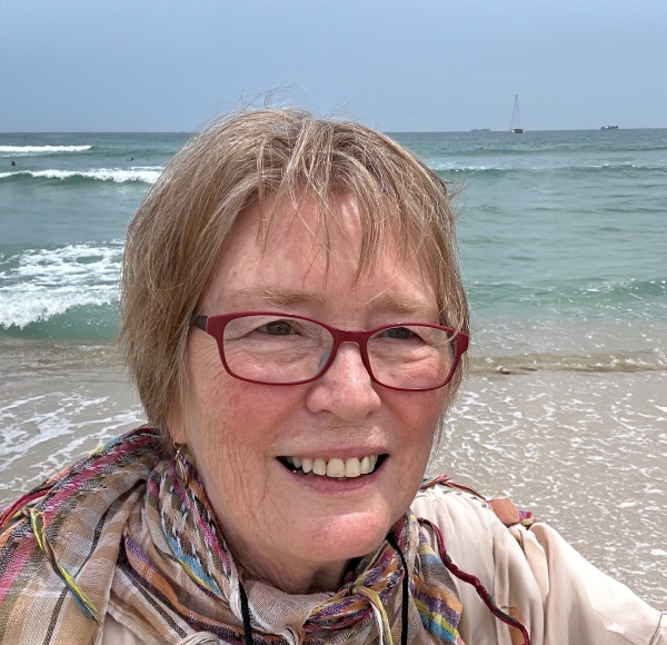 Woman smiling at the beach with waves behind her