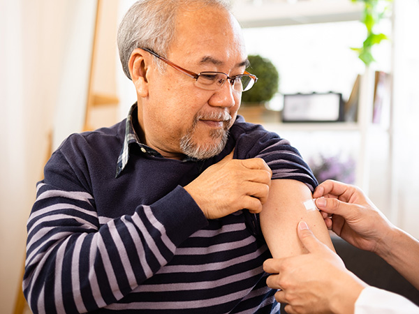 Elderly senior Asian man getting influenza flu shot vaccination at home