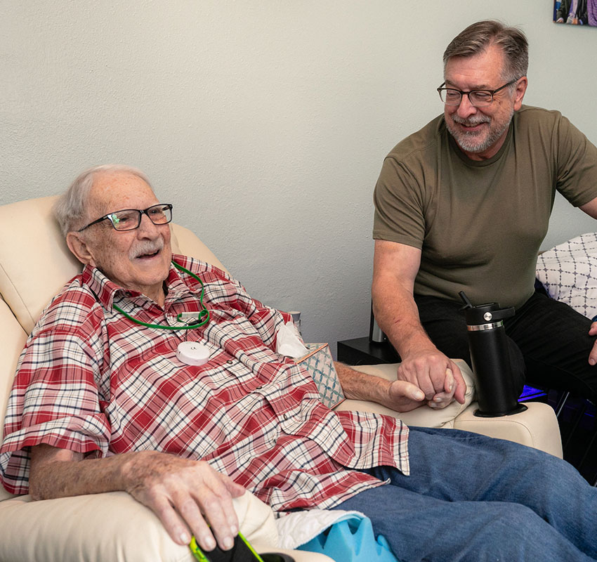 A Housecall Providers Hospice patient smiles with his son during a house call